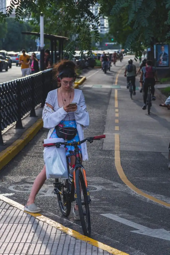 Young woman on a bicycle checks her phone on a busy Buenos Aires street.